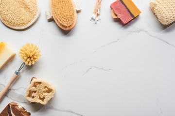 top view of ear sticks, bath sponges, soap, loofah and body brushes on marble surface