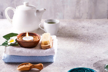 Spa resort therapy composition. Burning candles, towel, tea set and flower on a stone background, copy space