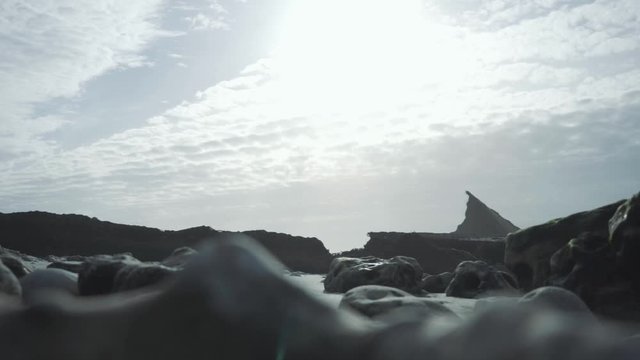 Two slow-motion shots on a wild beach with ruins in background