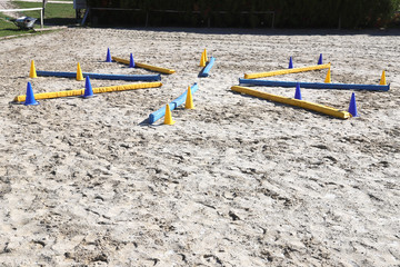 Colorful barriers on the ground for jumping horses and riders at riding school as a background
