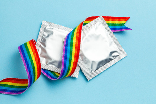 Condoms and LGBT rainbow ribbon pride tape symbol. Blue background - Powered by Adobe