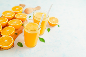 freshly squeezed orange juice in glasses on the kitchen table with slices of oranges, concept of diet and healthy lifestyle