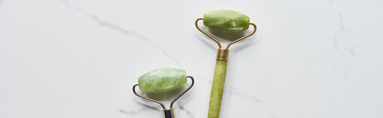 panoramic shot of jade facial rollers on marble surface