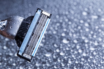 Razor close-up with water drops on a gray background.