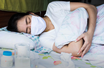 A woman is sick and sleeping on bed
