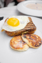 Tasty breakfast - toast, fried eggs, cheese pancakes on a white plate
