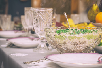 Festive table setting with crystal glasses and plates. Selective focus