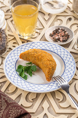 deep fried fish in batter with parsley and glass of lemonade on oriental wooden table