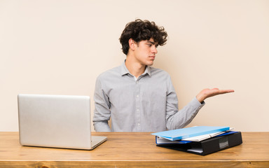 Young student man with a laptop holding copyspace with doubts