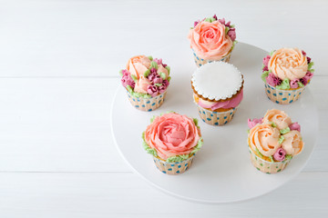 Cupcakes with colorful cream flowers on white background. Picture for a menu or a confectionery catalog.