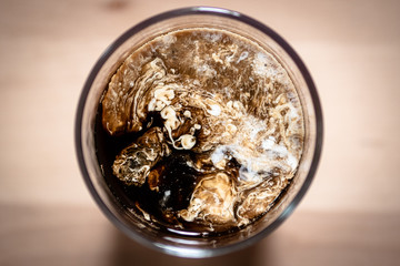 Top view of coffee in glass with milk on wooden board background