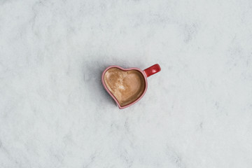  cup of coffee in the heart form in the snow. New Year Christmas and winter concept