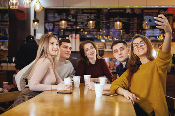 Five young handsome students sitting in a cafe.