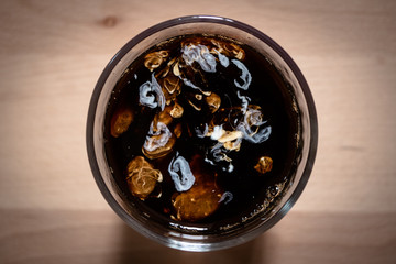 Top view of coffee in a glass with milk on a wooden board background