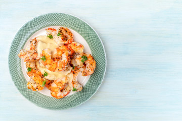 Shrimps with a sauce, shot from above on a light blue background with copy space