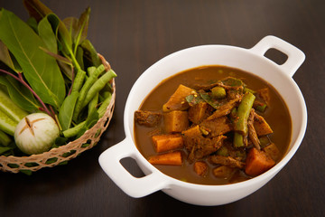 Thai food : The viscera of mackerel fish paunch hot spicy curry or fish organs sour soup with vegetables on wooden table, Thai language is Kang Tai Pla