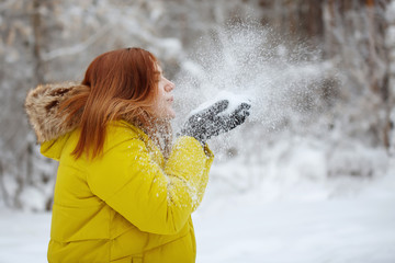 Young, pretty, cheerful red long-haired woman in winter outside.
