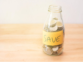coins in glass  bottle on wooden table.Saving money concept