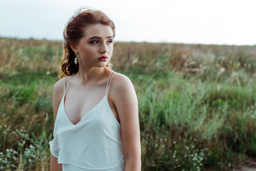 pretty and young redhead woman in green field