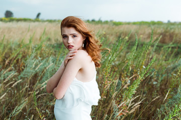 beautiful redhead woman in white dress looking at camera