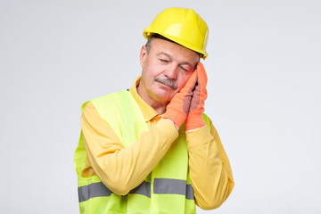 Senior hispanic repairman in yellow helmet is tired and sleepy after hard working day. I need a rest concept. Studio shot