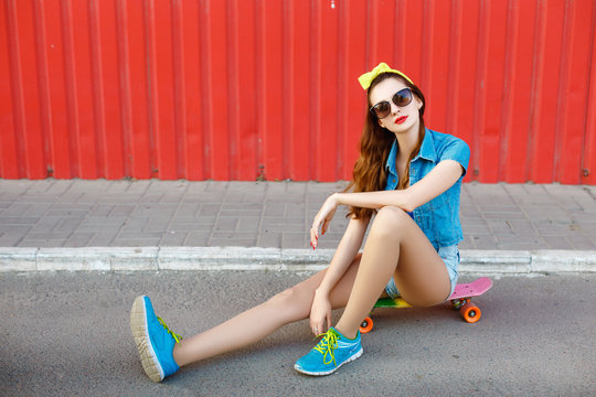 Girl sitting on a skateboard outdoors