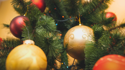 Closeup toned image of red and golden sparkling ball hanging on Chrismtas tree. Perfect abstract background for winter holidays or celebrations