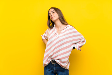 Young woman over isolated yellow background suffering from backache for having made an effort
