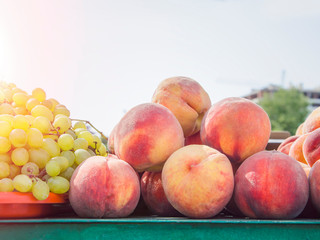 ripe peaches with green grapes at an outdoor market