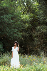 selective focus of beautiful african american girl touching curly hair in field with wildflowers