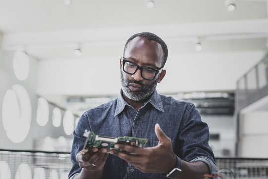 Closeup of African American adult male computer engineer holding motherboard