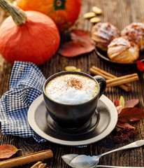 Pumpkin spice latte, coffee with the addition of pumpkin puree, aromatic spices and whipped cream  sprinkled with cinnamon  in a cup on a wooden table. Delicious and healthy hot drink