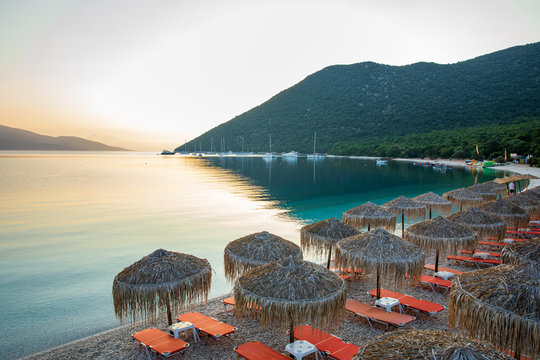 Summer sunny morning sunbeds and umbrellas of amazing Antisamos beach on the Kefalonia island, Ionian sea, Greece.