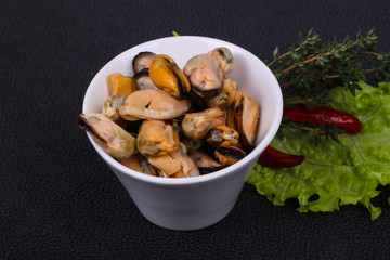 Pickled mussels in the bowl served pepper, garlic and salad