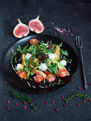 salad on a plate: arugula, cherry tomatoes, white figs, grated cheese, black grapes