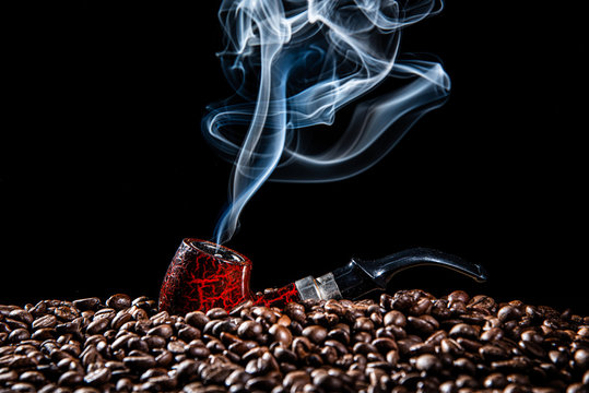 beautiful lighting of dark red vintage smoking pipe with beauty white smoke shape on dark brown coffee beans in black background stock photo