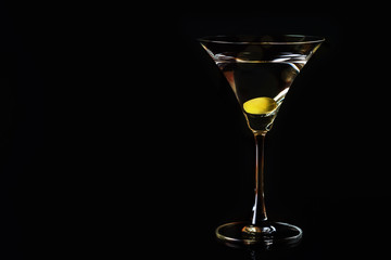 Martini glass and olives on a black background. Selective focus. Close up.