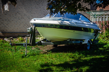 sport boat on a trailer parked in the shade