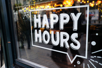 white 'happy hours' sign on restaurant window with beautiful bokeh balls in the background