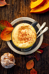 Pumpkin spice latte, coffee with the addition of pumpkin puree, aromatic spices,  sprinkled with cinnamon  in a cup on a wooden table, top view. Delicious and healthy hot drink