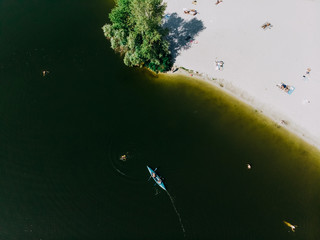 Shooting from the drone of a beach, people and a floating kayak.