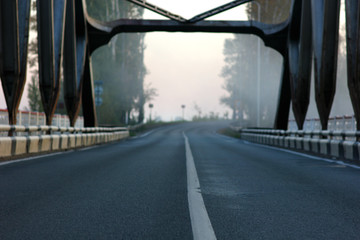 view of the road on the bridge over the misty river