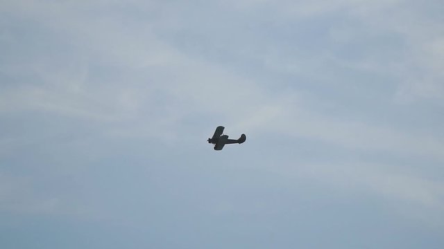 A small plane aircraft biplane flying in the blue sky. Slow motion