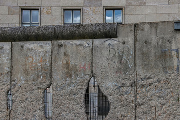 Section of Berlin Wall with holes looking at former Reichstag building in background nobody
