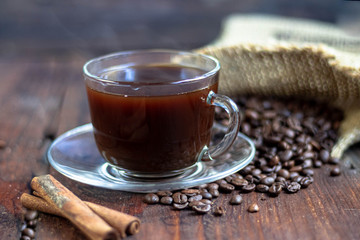 Coffee in a transparent cup. Hot, invigorating drink. Near cones in sparkles, coffee beans are scattered.