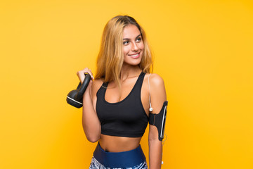 Young sport woman making weightlifting with kettlebell over isolated yellow background