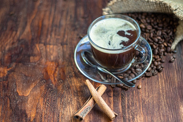 Coffee in a transparent cup. Hot, invigorating drink. Near cones in sparkles, coffee beans are scattered.