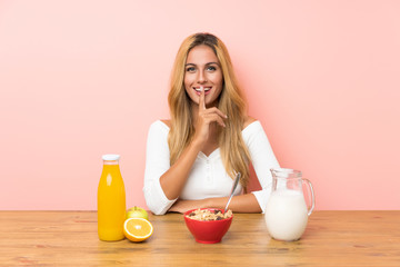 Young blonde woman having breakfast milk doing silence gesture