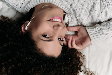 Woman wearing earphones while lying in bed