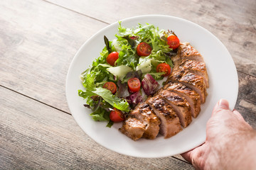 Grilled chicken breast with vegetables on a plate on wooden table
